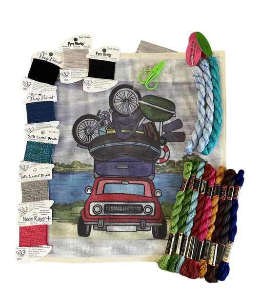Travel-inspired needlepoint kit with a stacked camper design, accompanied by diverse threads including Neon Rays and Fyre Werks.